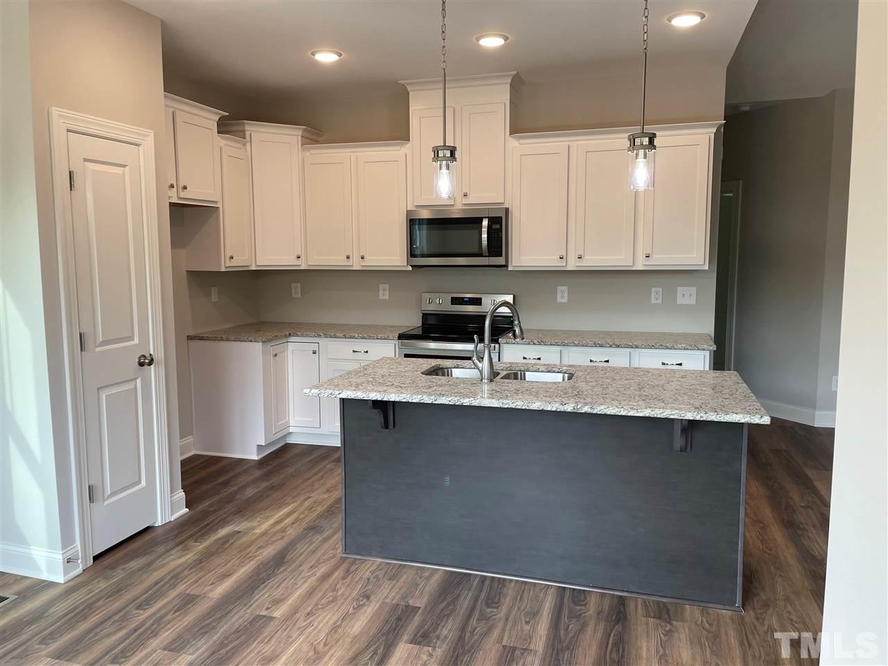 1820 Bryantown Road Spring Hope, NC 27882 - Photo 9 of 23 a kitchen with stainless steel appliances a sink stove refrigerator and white cabinets with wooden floor