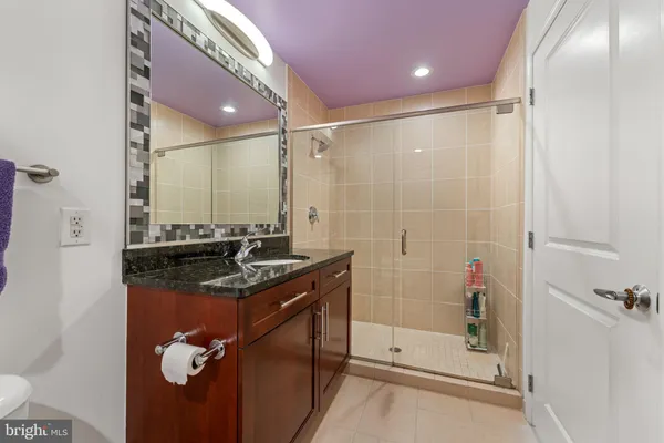 a bathroom with a granite countertop sink a mirror and shower