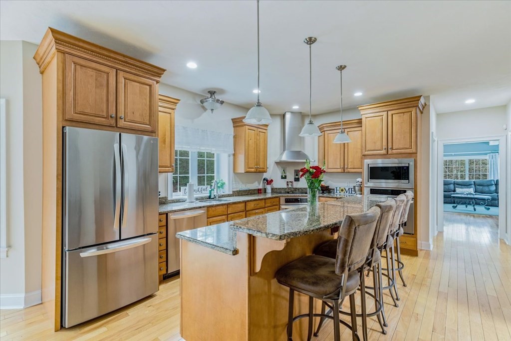 176 Marion Road Middleboro, MA 02346 - Photo 8 of 41 a kitchen with granite countertop a refrigerator a stove a kitchen island with a dining table and wooden floors