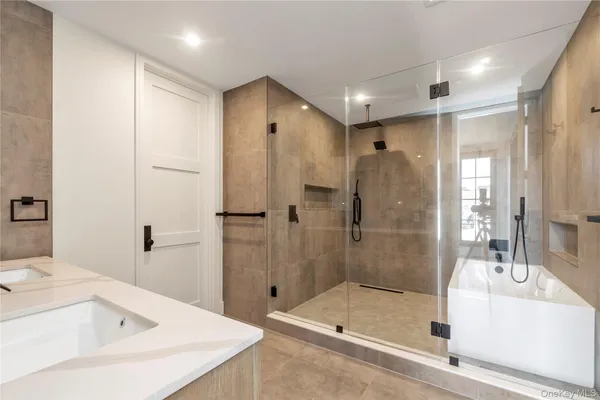 a bathroom with a tub sink shower and mirror