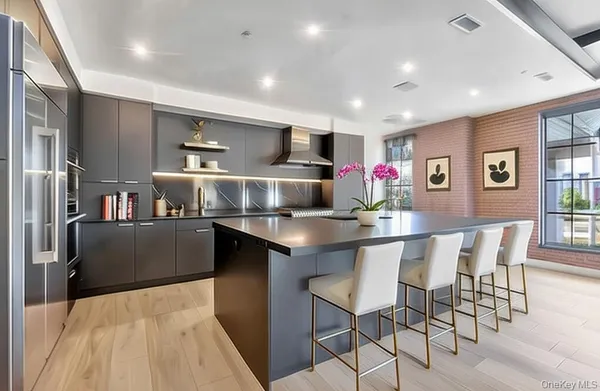 a kitchen with stainless steel appliances kitchen island granite countertop a dining table chairs and a refrigerator