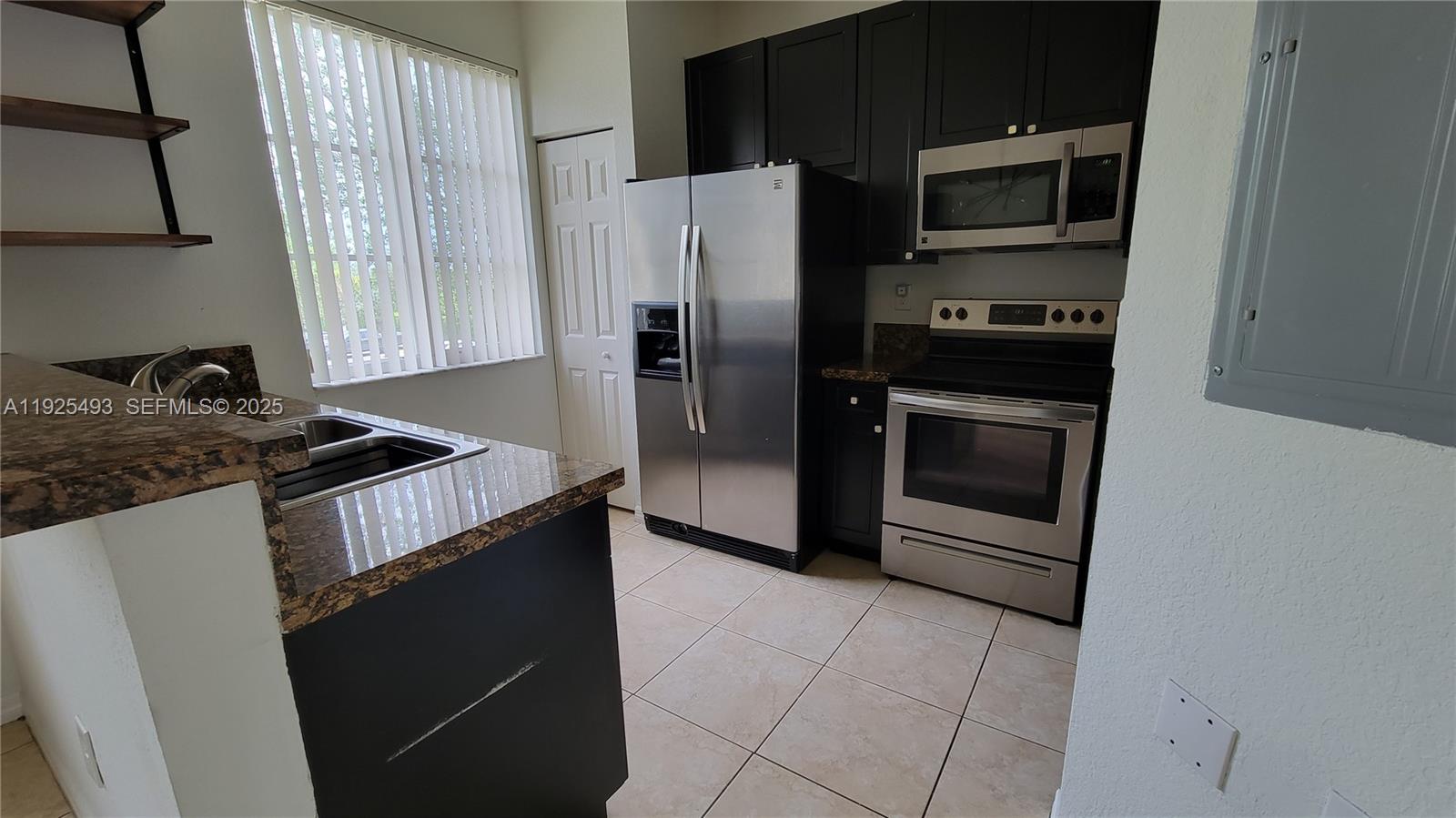 12600 Southwest 50th Court, Unit 437 Miramar, FL 33027 - Photo 3 of 24 a kitchen with granite countertop a stove and a refrigerator