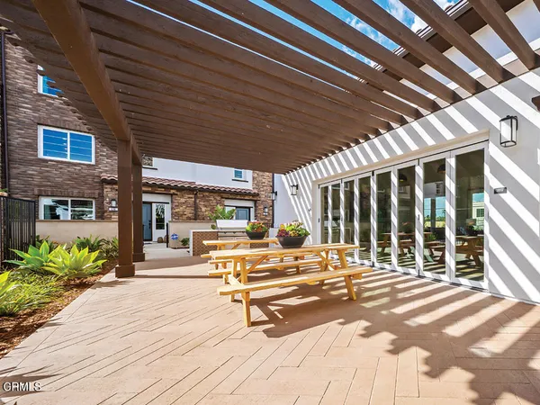 a view of a patio with table and chairs potted plants and floor to ceiling window
