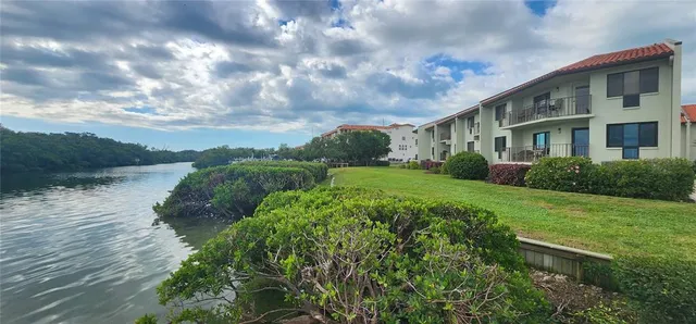 a view of a white house with a big yard and potted plants