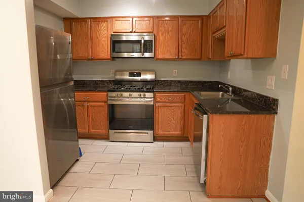 a kitchen with stainless steel appliances granite countertop a refrigerator stove and sink