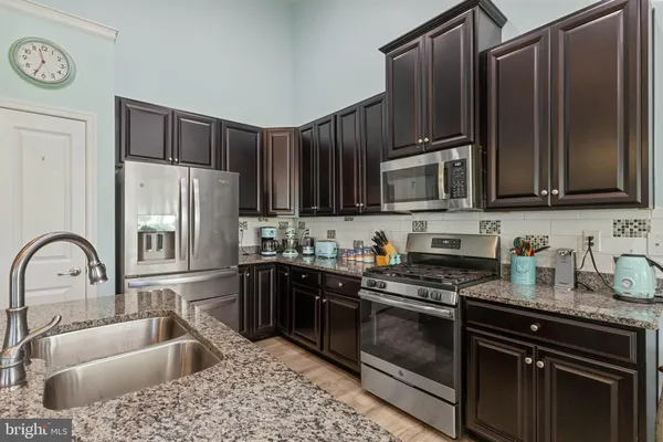 a kitchen with granite countertop a sink stove and refrigerator