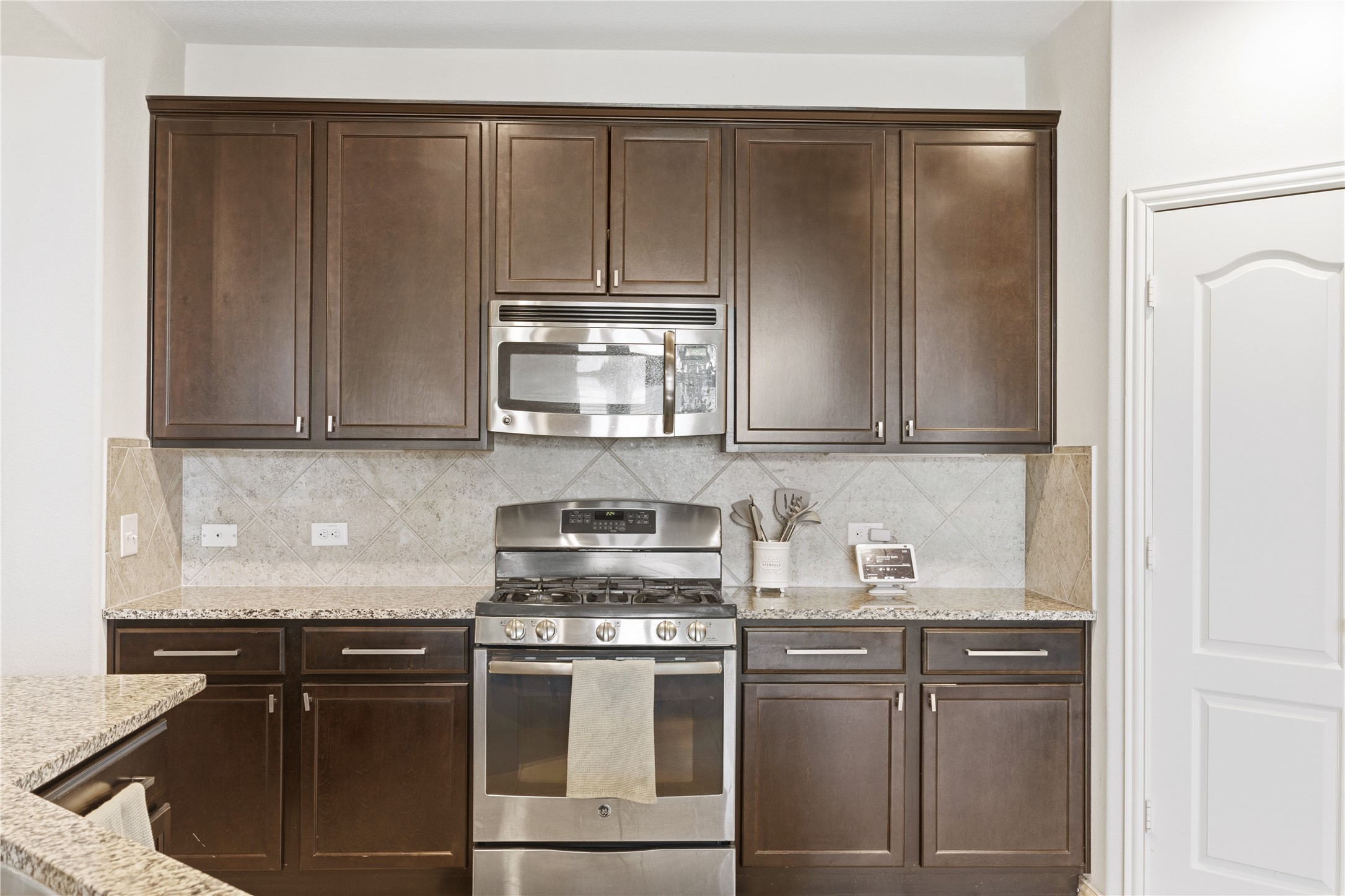 486 Pond View Pass Buda, TX 78610 - Photo 7 of 39 Kitchen featuring dark wood-finish cabinetry, granite countertops, and a full tile backsplash