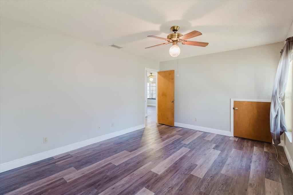 28330 Peterson Camp Road Brooksville, FL 34601 - Photo 30 of 81 a view of an empty room with wooden floor and a ceiling fan