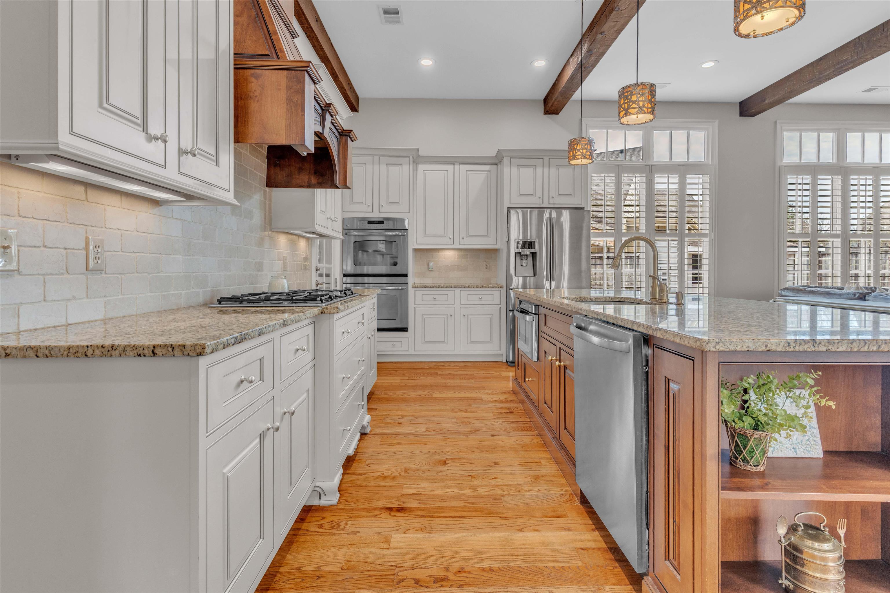 528 Althea Lane Collierville, TN 38017 - Photo 6 of 36 Kitchen featuring two tone cabinetry, a spacious island, light stone counters, stainless steel appliances, and light wood finished floors