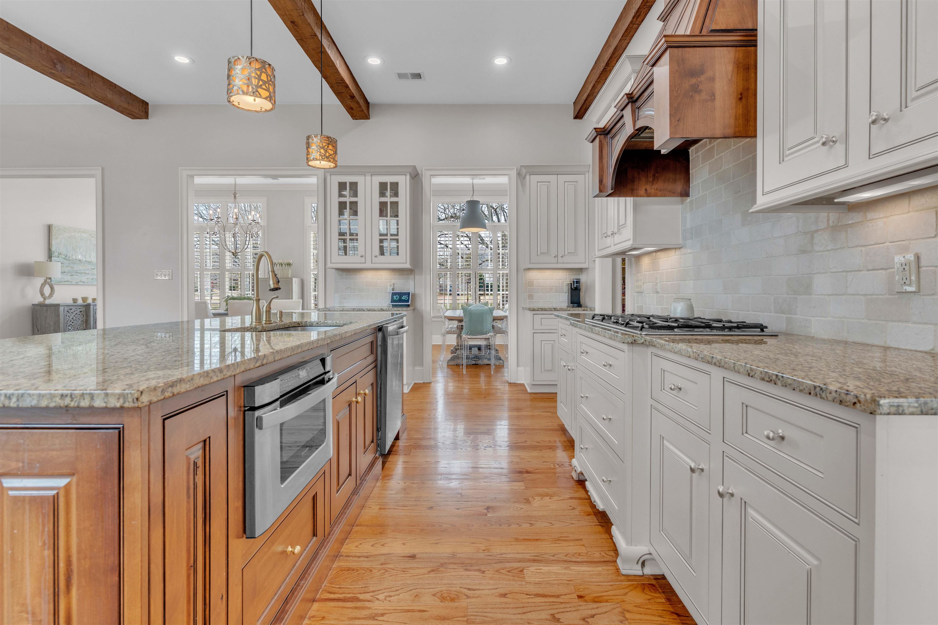 528 Althea Lane Collierville, TN 38017 - Photo 7 of 36 Kitchen featuring dual tone cabinets, light stone counters, glass insert cabinets, backsplash, and an island with sink