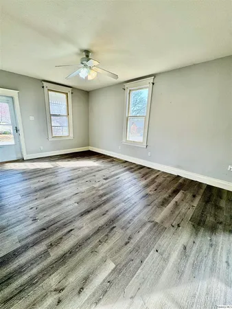 a view of an empty room with wooden floor and a window