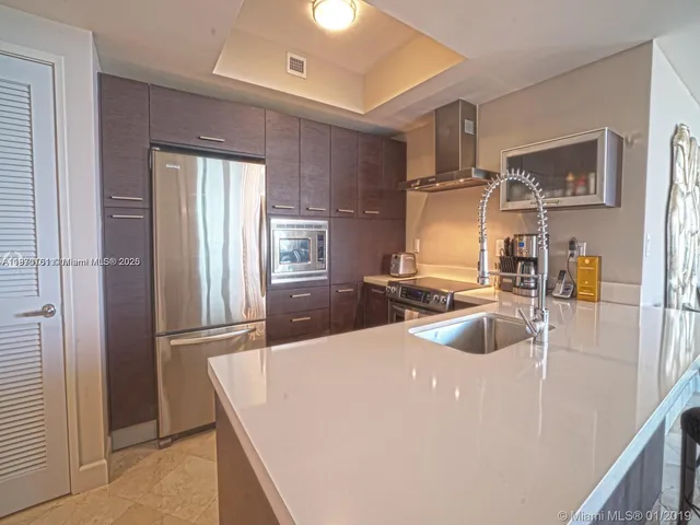 a kitchen with stainless steel appliances granite countertop a sink and a refrigerator