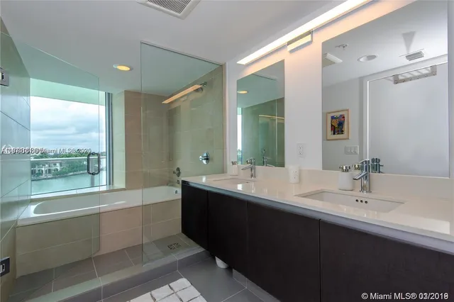 a bathroom with a double vanity sink mirror and bathtub