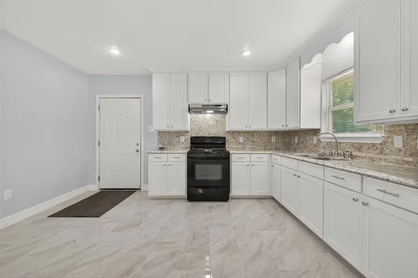 a kitchen with granite countertop white cabinets and stainless steel appliances