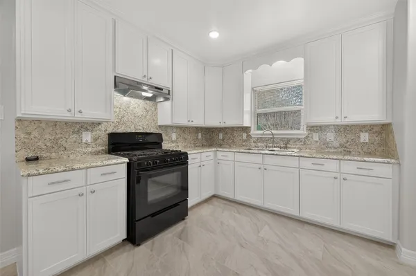 a kitchen with granite countertop white cabinets and sink