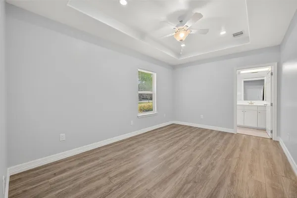 an empty room with wooden floor and ceiling fan