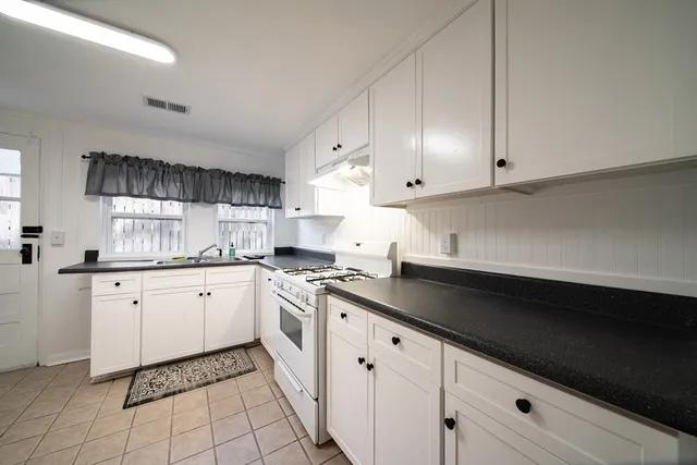 a kitchen with granite countertop white cabinets and white appliances