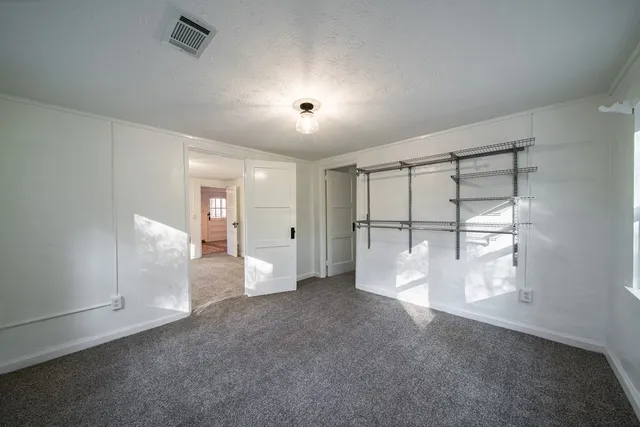 an empty room with chandelier fan and windows