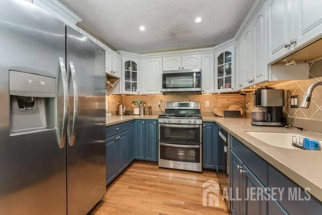 a kitchen with stainless steel appliances granite countertop a refrigerator a stove and a sink