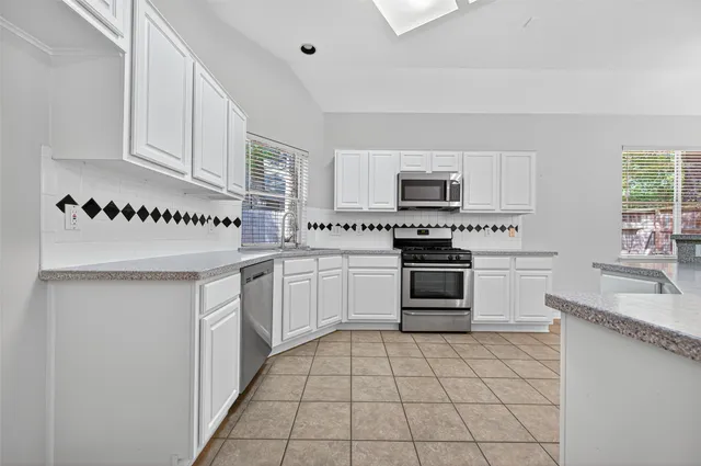 a kitchen with granite countertop a stove top oven and cabinets