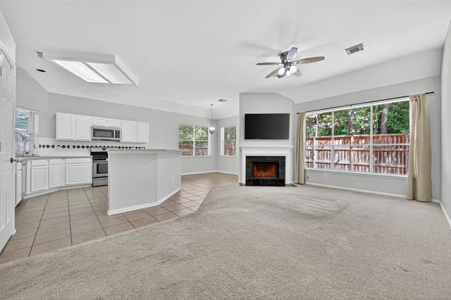 a view of a livingroom with a fireplace a ceiling fan a fireplace and windows