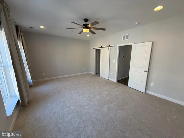 an empty room with chandelier fan and windows