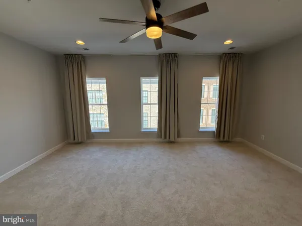 an empty room with windows and a chandelier fan