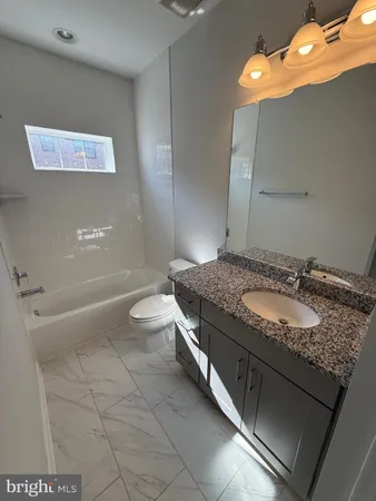 a bathroom with a granite countertop sink a toilet and bathtub