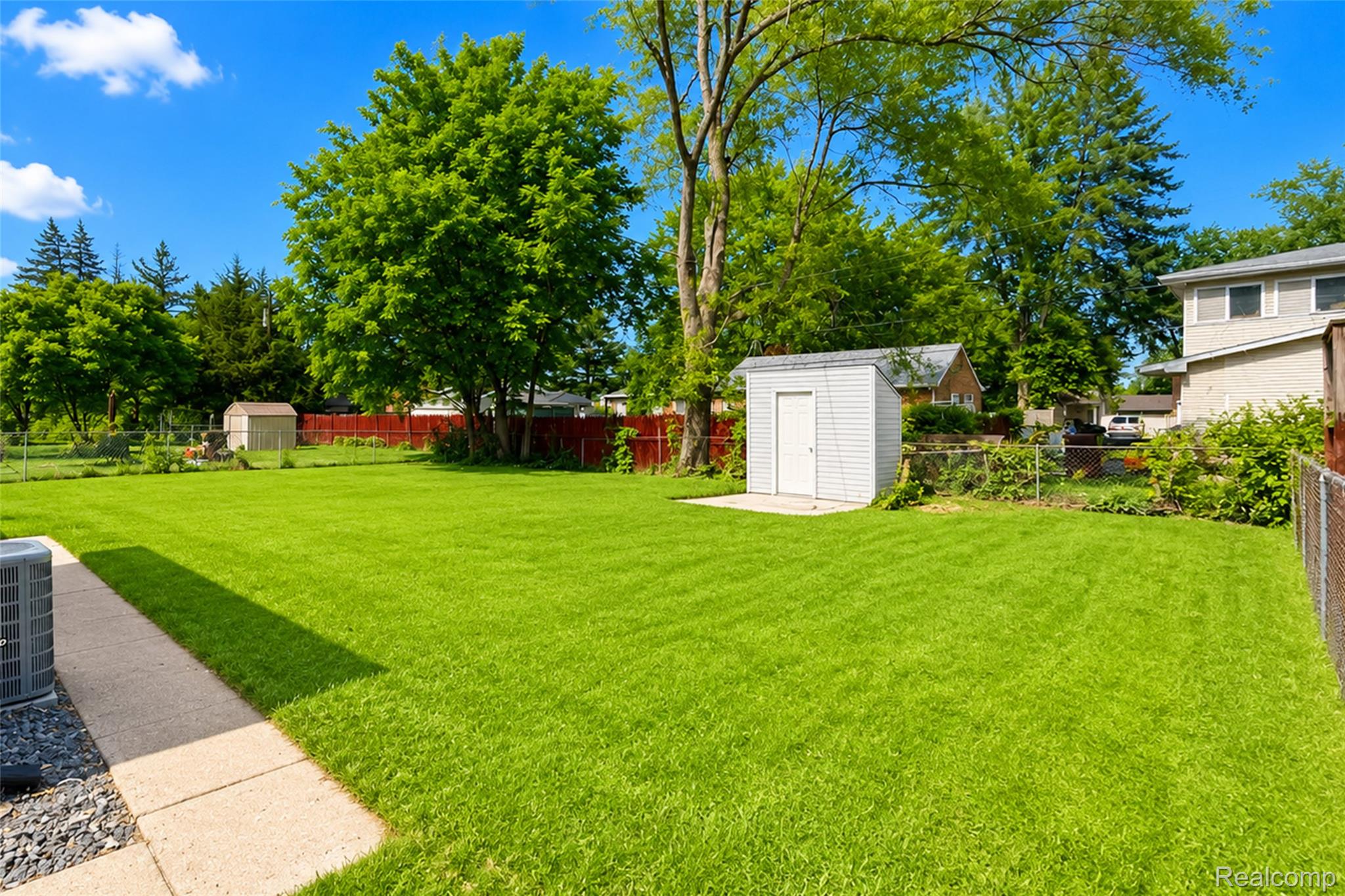 201 Cardwell Street Inkster, MI 48141 - Photo 5 of 41 Expansive green lawn featuring a white storage shed on a concrete pad, mature trees, and a concrete patio