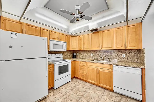 a kitchen with stainless steel appliances granite countertop a refrigerator a sink a stove and white cabinets