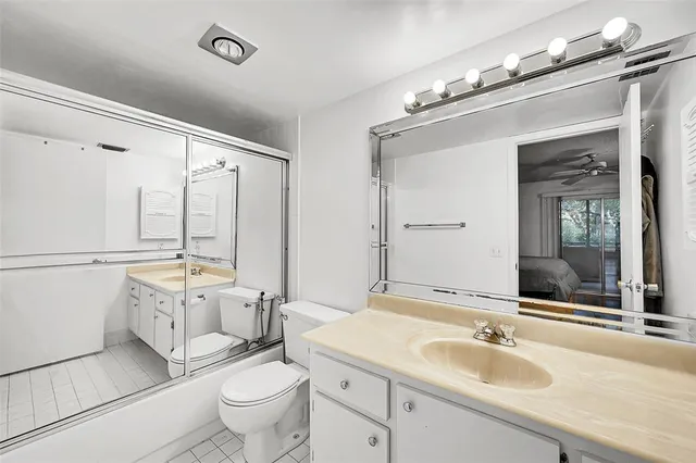 a bathroom with a granite countertop sink mirror vanity and toilet