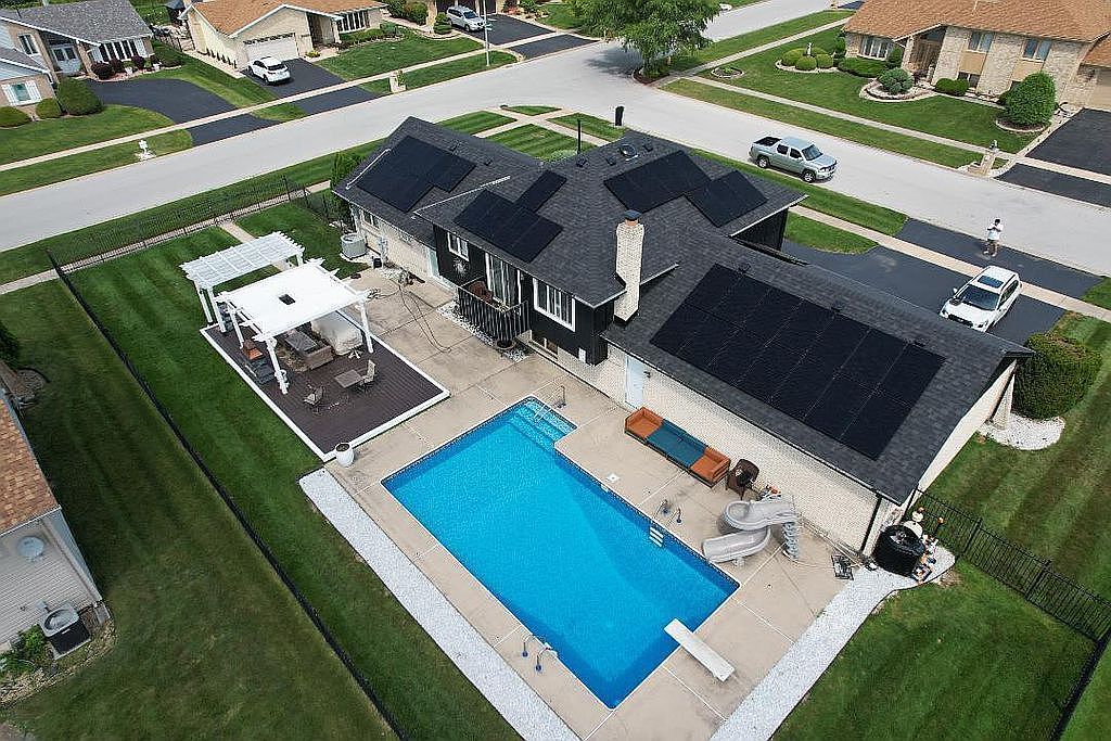 an aerial view of a house a yard patio swimming pool and outdoor seating