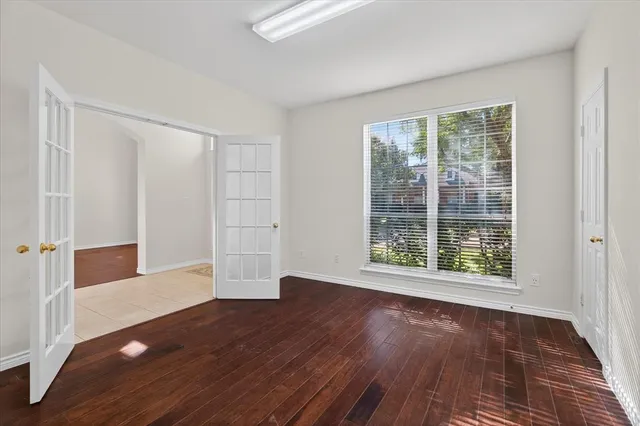 an empty room with wooden floor and windows
