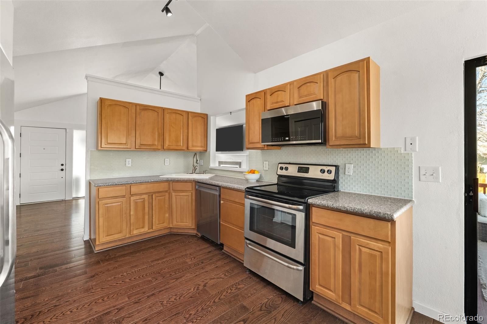 6404 Raleigh Street Arvada, CO 80003 - Photo 12 of 50 a kitchen with stainless steel appliances granite countertop a stove a sink and a microwave