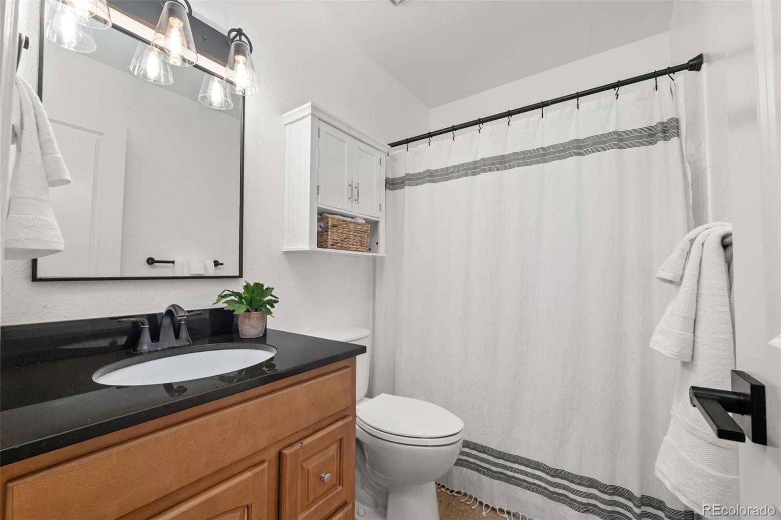 6404 Raleigh Street Arvada, CO 80003 - Photo 27 of 50 a bathroom with a granite countertop sink and a mirror