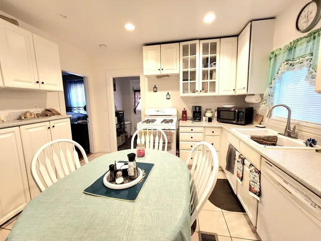 a kitchen with stainless steel appliances kitchen island granite countertop a sink and dishwasher a stove top oven with white cabinets