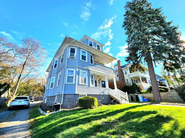 a view of a house with a big yard plants and large trees