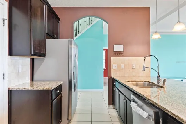 a large kitchen with stainless steel appliances kitchen island granite countertop a refrigerator and a sink