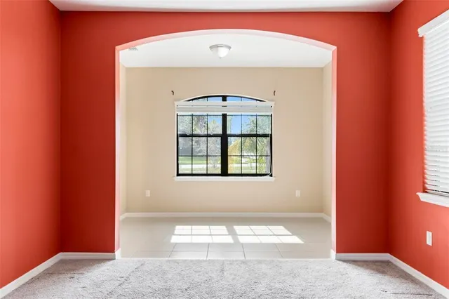 a view of an empty room with window and chandelier fan