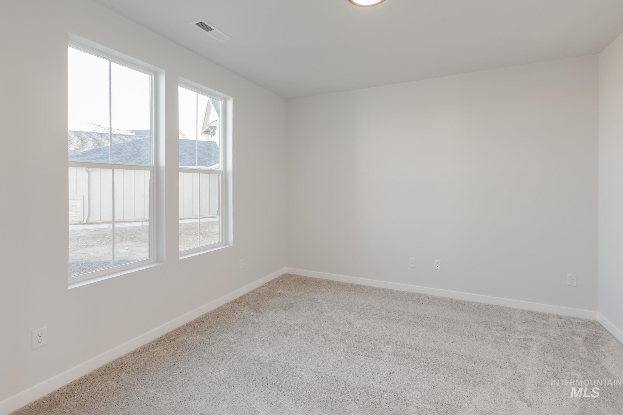 1639 Celina Street Middleton, ID 83644 - Photo 8 of 19 Spacious room featuring two large windows, neutral-toned carpeting, white baseboards, and a flush-mount ceiling light fixture
