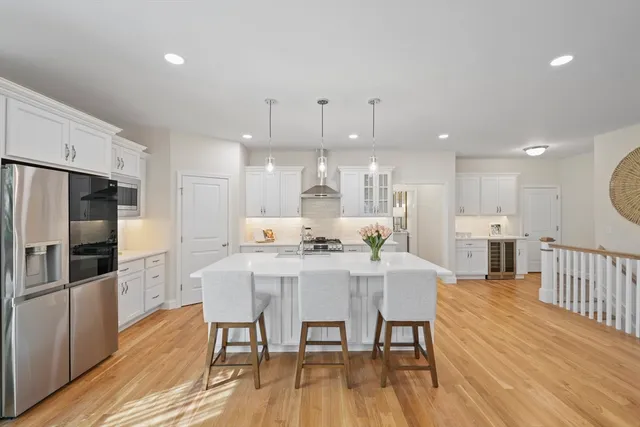 a kitchen with stainless steel appliances kitchen island granite countertop a dining table chairs refrigerator and sink