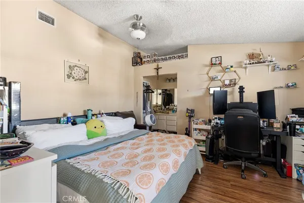 a bedroom with bed a flat tv screen and a dresser