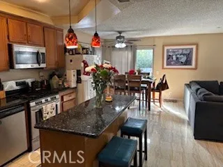 a kitchen with stainless steel appliances granite countertop a stove a refrigerator a dining table and chairs with wooden floor