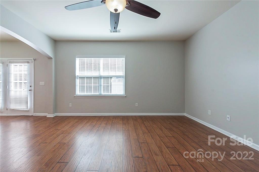 705 Jones Branch Road Fort Mill, SC 29715 - Photo 5 of 18 an empty room with wooden floor chandelier fan and windows