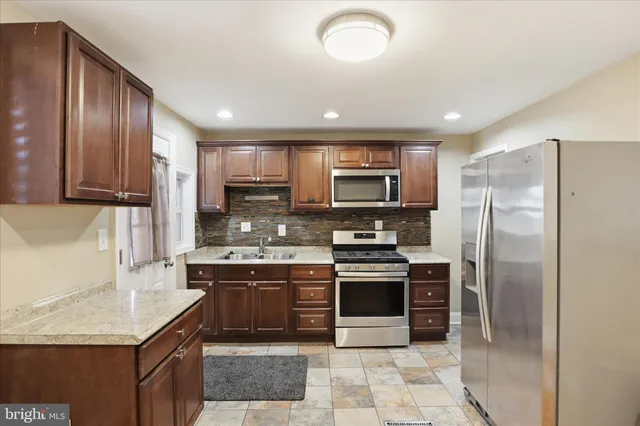 a kitchen with stainless steel appliances granite countertop a refrigerator a stove a sink and a microwave