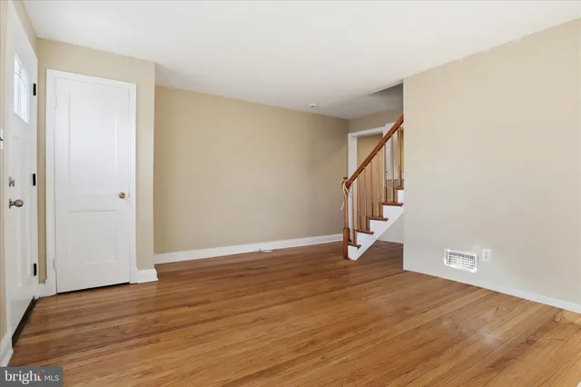a view of an empty room with wooden floor and stairs
