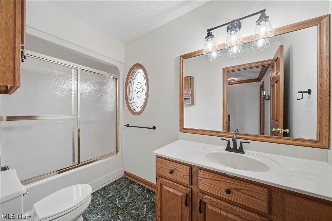 4764 Young Road Stow, OH 44224 - Photo 23 of 41 Bathroom featuring a wood-framed vanity mirror, a three-light fixture, wood cabinetry, a white countertop with an undermount sink, and green patterned floor tiles