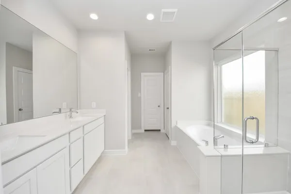 a bathroom with a double vanity sink a large mirror and a bathtub