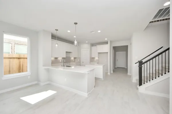 a large white kitchen with a sink and dishwasher a stove a refrigerator with wooden floor