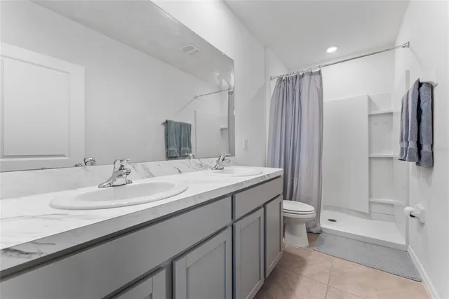 a bathroom with a double vanity sink toilet and shower